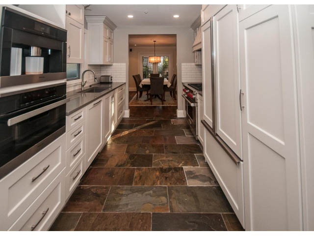 Bright kitchen with white cabinets, dark stone countertops, and a view of the dining area. - 14 West 13th Ave, Vancouver East Side