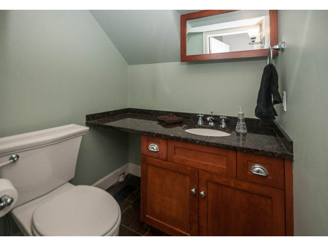 Bright bathroom with dark granite countertops and wooden cabinets. - 14 West 13th Ave, Vancouver East Side