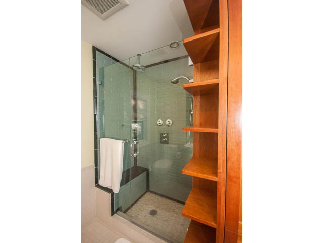 Bright bathroom with glass shower and wooden shelving. - 14 West 13th Ave, Vancouver East Side