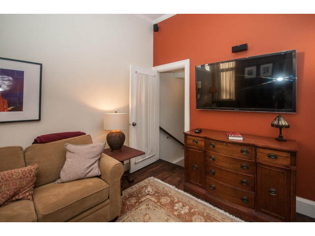 Living room with wooden dresser, flat-screen TV, and cozy sofa. - 14 West 13th Ave, Vancouver East Side