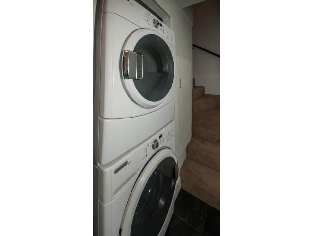 Laundry room with stacked washer and dryer, clean and organized. - 14 West 13th Ave, Vancouver East Side