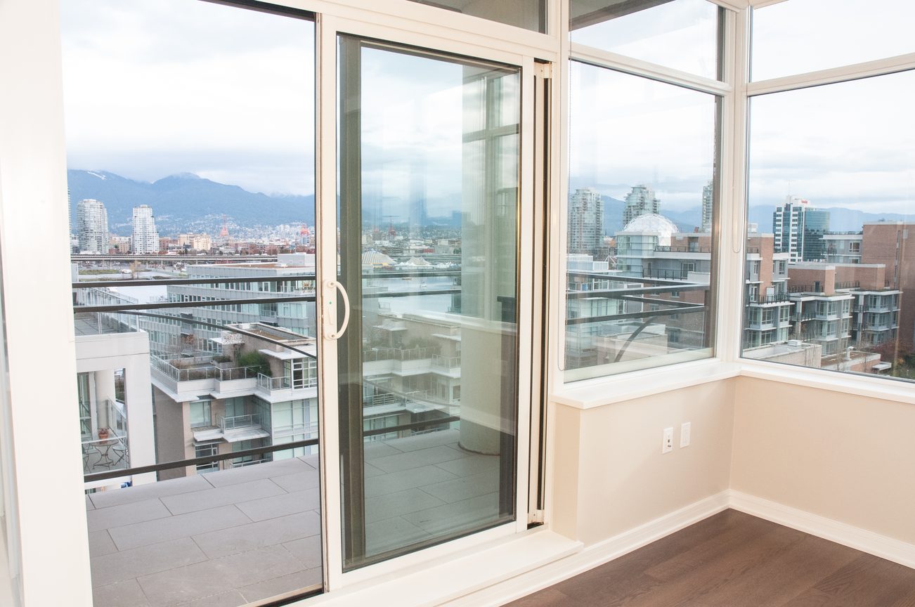 Bright living room with large windows offering a stunning city view and modern furnishings. - 1010-181 West 1st Avenue, Vancouver West Side