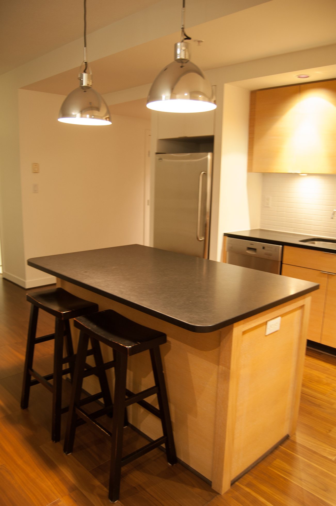 Bright kitchen with wooden island, black countertops, and pendant lights. - 1901-1055 Homer Street, Vancouver Downtown