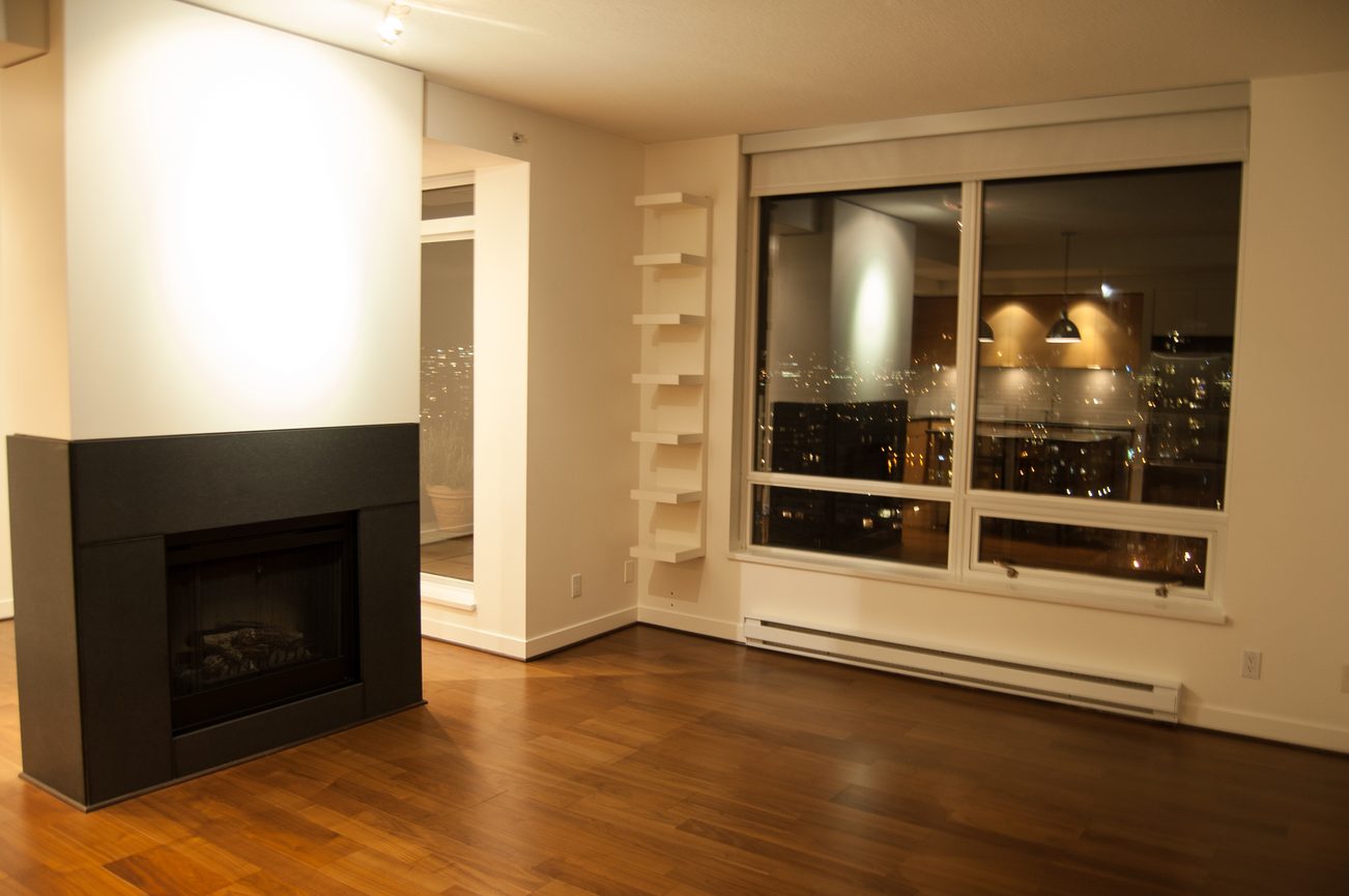 Spacious living room with hardwood floors, city view, and modern fireplace. - 1901-1055 Homer Street, Vancouver Downtown