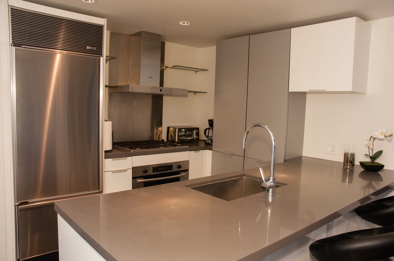 Bright kitchen with modern stainless steel appliances, sleek countertops, and a large island. - 2306-788 Richards, Vancouver Downtown