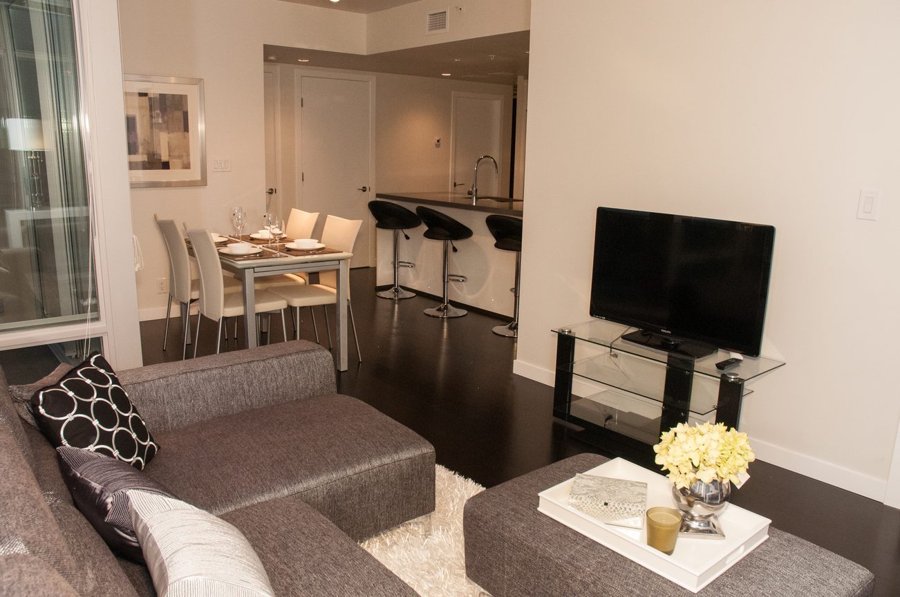 Open-concept living and dining area with modern furnishings, hardwood floors, and a city view. - 2306-788 Richards, Vancouver Downtown
