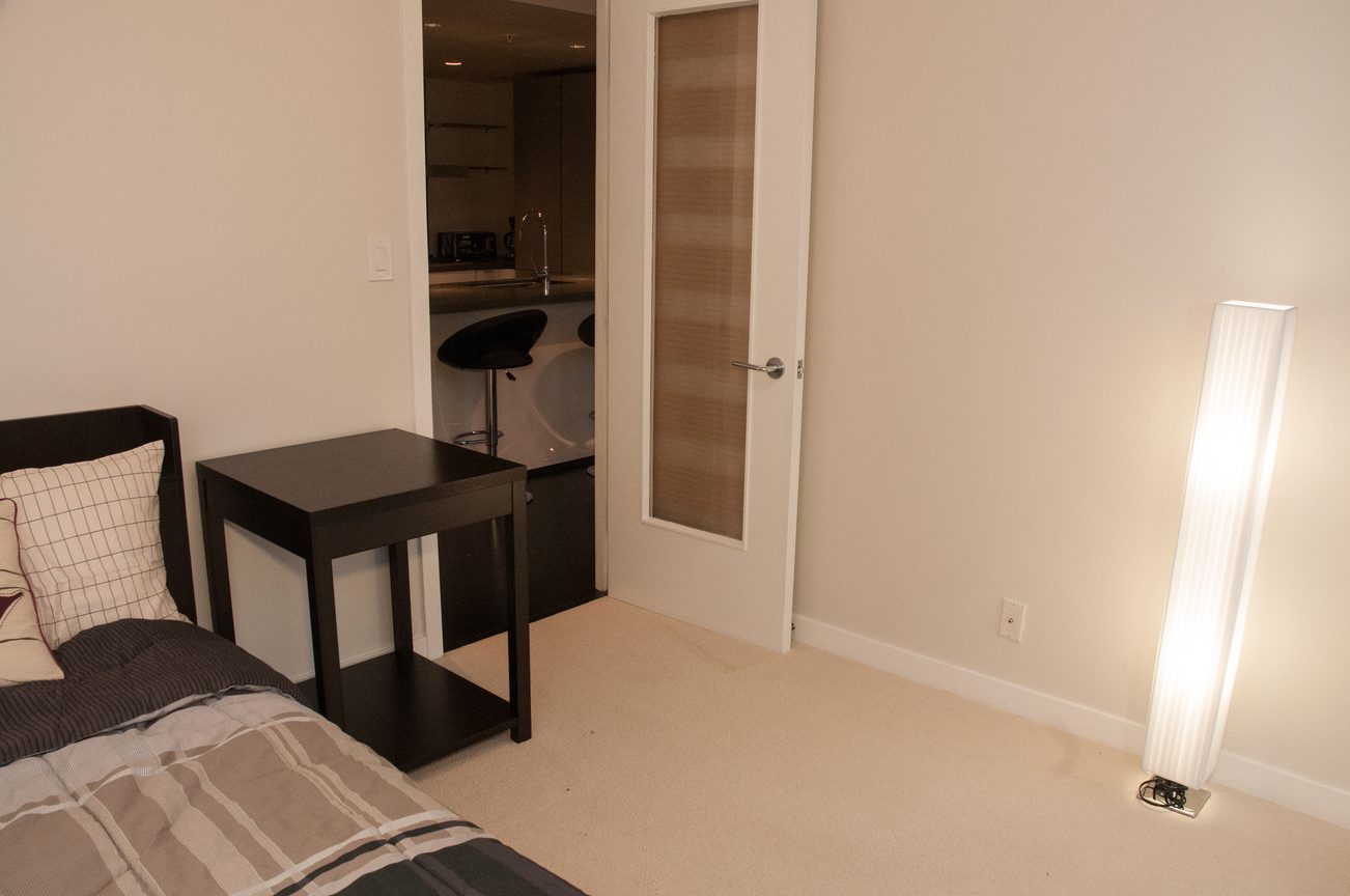 Bright bedroom with modern furniture and a view into a kitchen area. - 2306-788 Richards, Vancouver Downtown