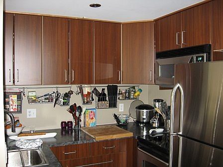 Bright kitchen with dark wood cabinets, granite countertops, and stainless steel appliances. - 405-811 Helmcken, Vancouver Downtown