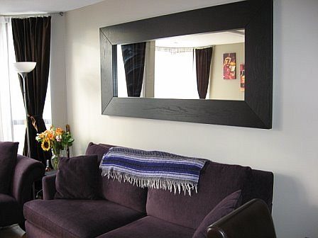 Bright living room with a large mirror and purple couch, featuring a cozy blanket and sunflowers. - 405-811 Helmcken, Vancouver Downtown