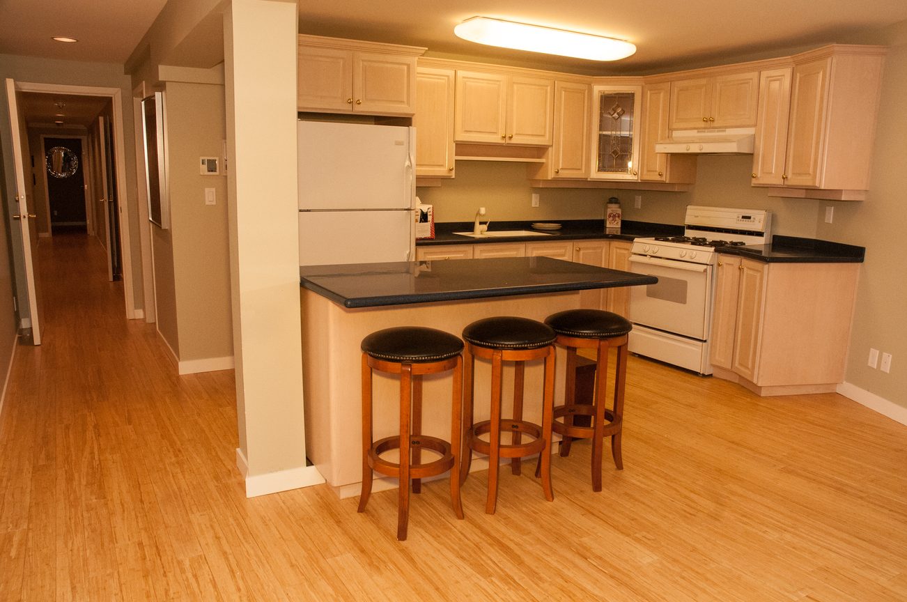 Bright kitchen with black countertops, light wood cabinets, and hardwood floors. - 829 Younette Drive, West Vancouver