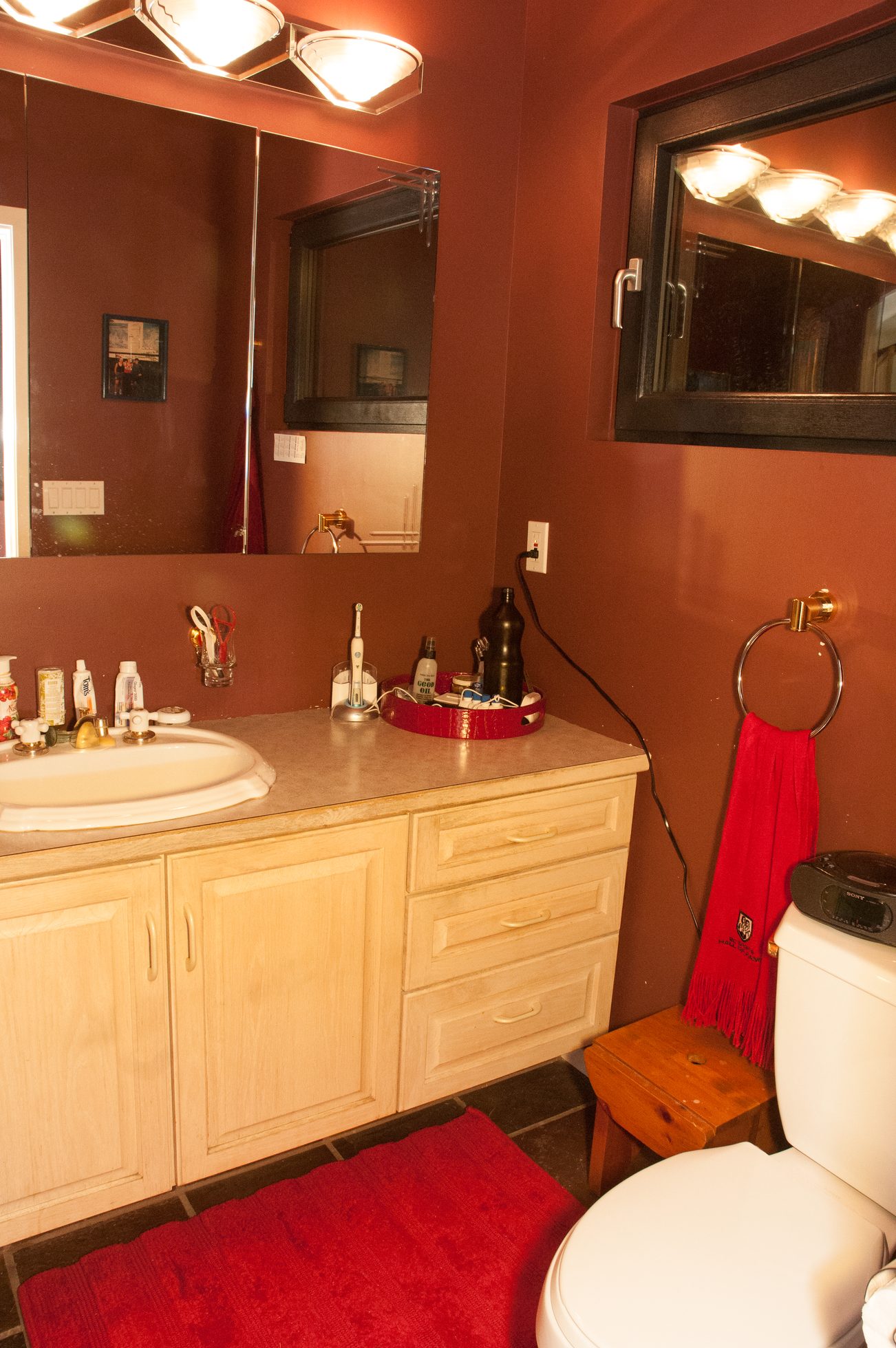 Bathroom with red walls, wooden cabinets, and a red rug. - 829 Younette Drive, West Vancouver