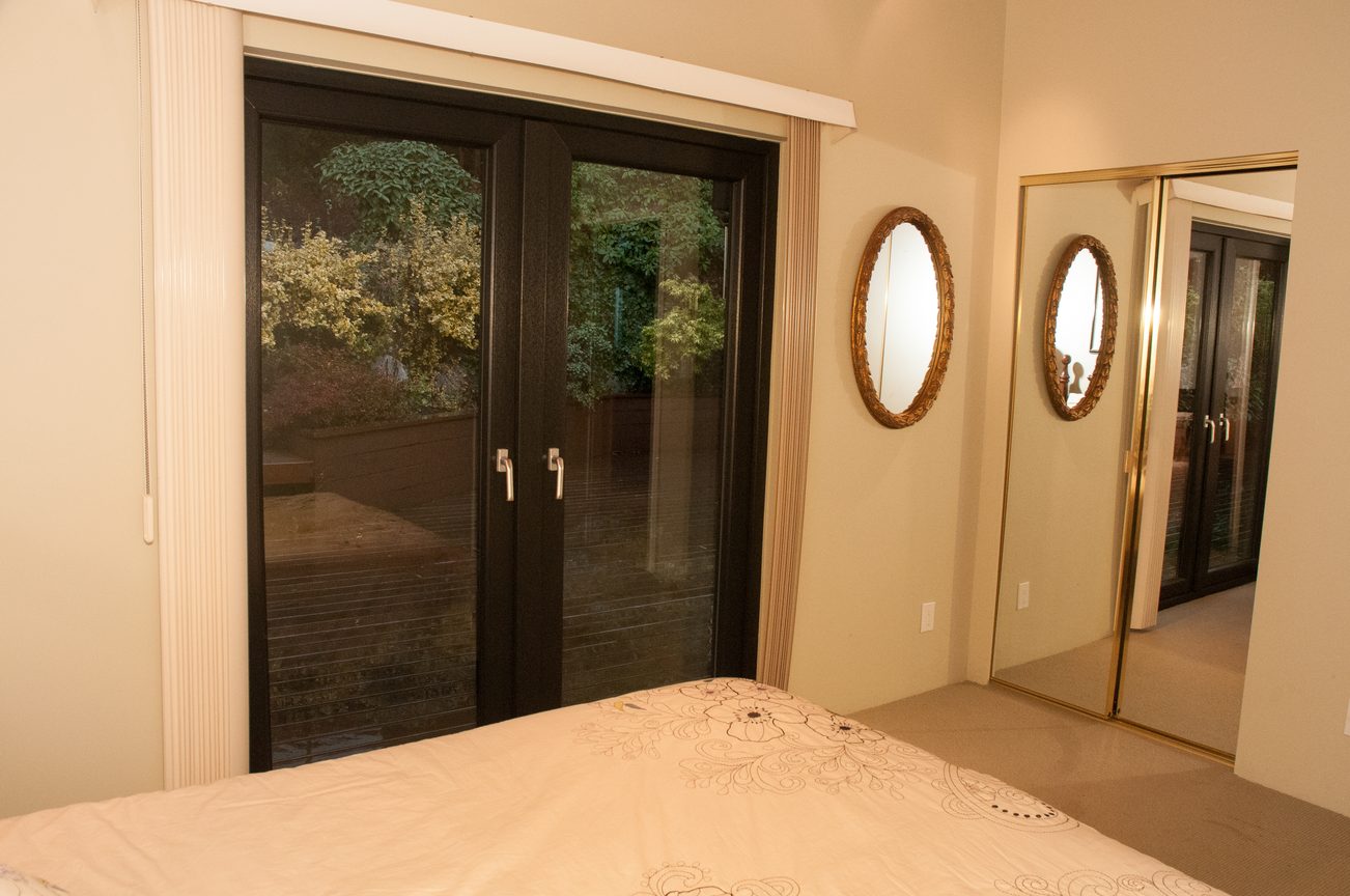 Furnished bedroom with large sliding doors leading to a garden view. - 829 Younette Drive, West Vancouver