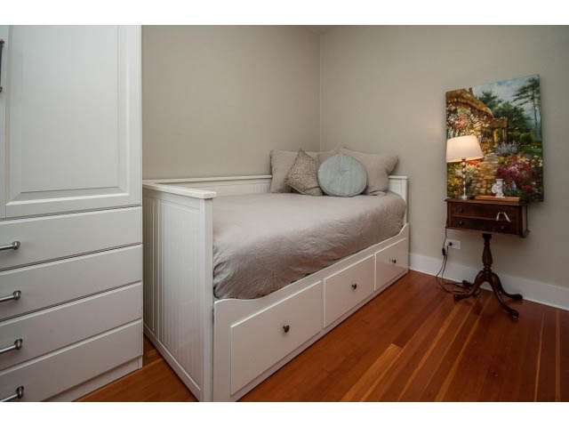 Furnished bedroom with built-in storage, hardwood floors, and a cozy corner setup. - Upper - 4838 Dunbar Street, Vancouver West Side