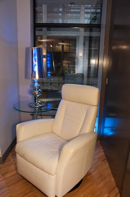 Furnished living room with white leather armchair, glass table, and city view. - 506-128 West Cordova St, Vancouver Downtown