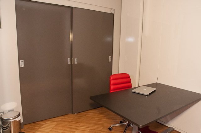 Modern kitchen with dark countertops and red chairs. - 506-128 West Cordova St, Vancouver Downtown