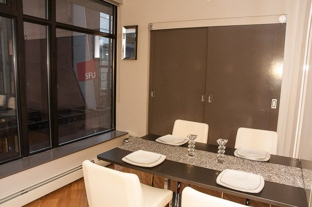 Furnished dining area with modern chairs and dark countertops, city view through large windows. - 506-128 West Cordova St, Vancouver Downtown