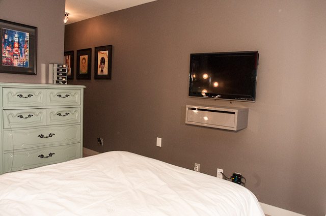 Furnished bedroom with a large TV mounted on the wall and a white dresser. - 506-128 West Cordova St, Vancouver Downtown