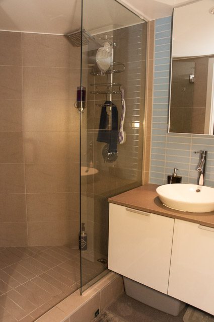 Modern bathroom with a sleek sink, glass shower, and light blue tiles. - 506-128 West Cordova St, Vancouver Downtown