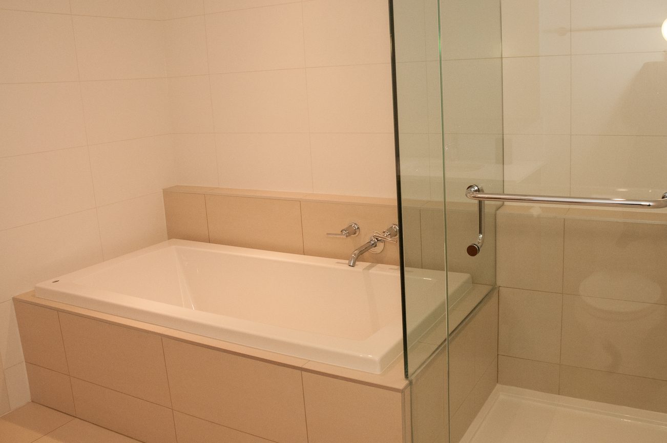 Modern bathroom with a sleek bathtub and glass shower enclosure. - 507-1677 Lloyd Avenue, North Vancouver