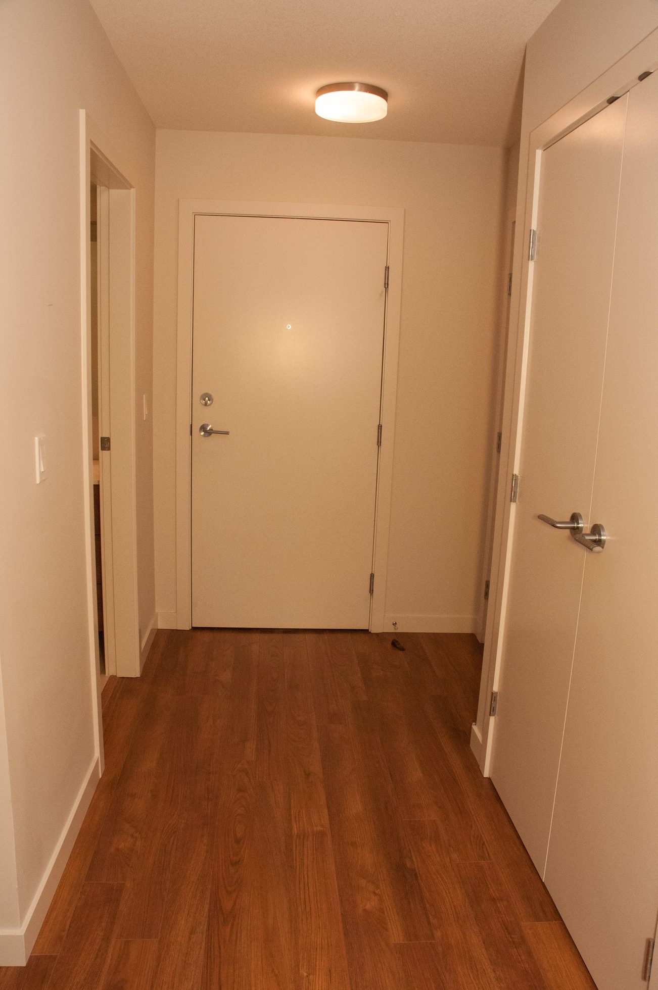 Furnished hallway with hardwood floors and a closed door leading to a room. - 507-1677 Lloyd Avenue, North Vancouver