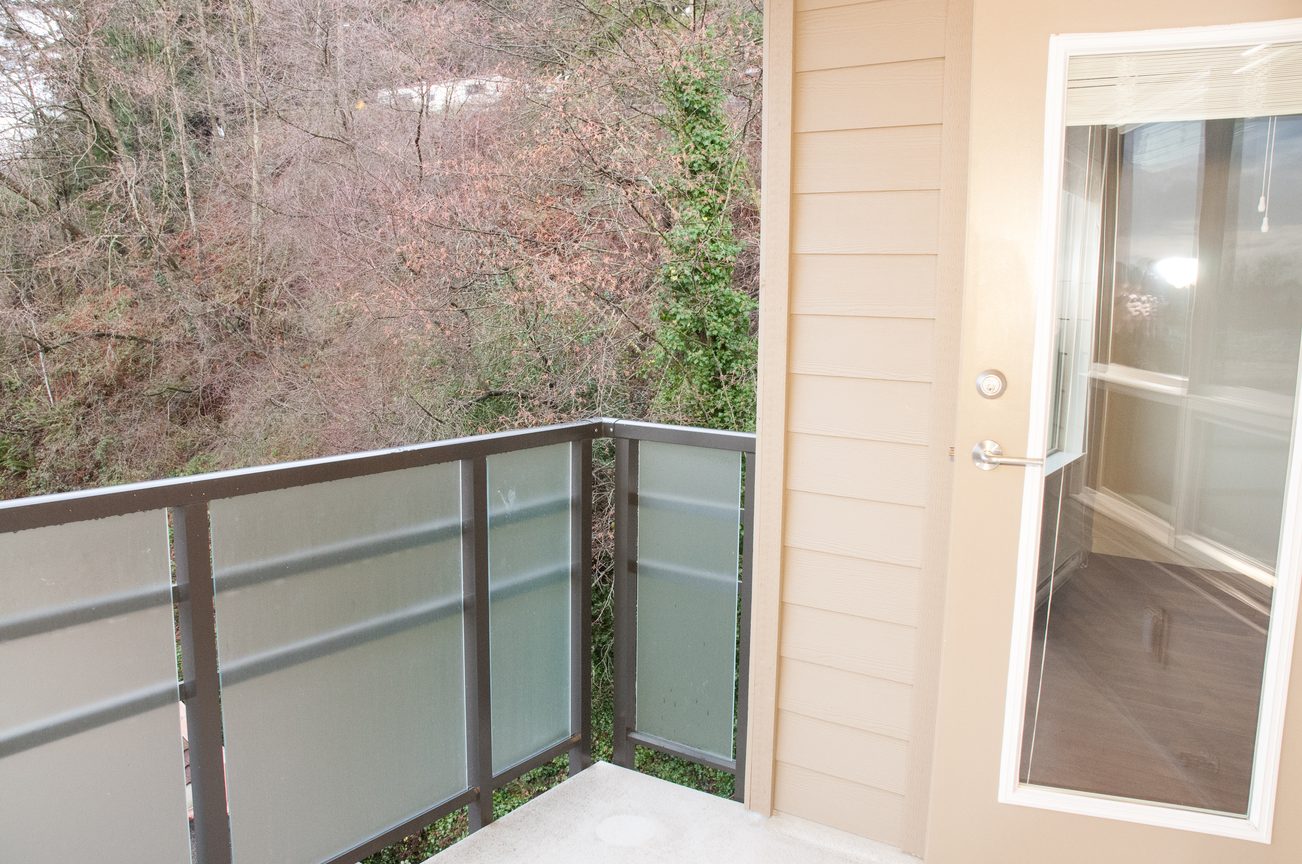 Balcony with glass railings and view of trees. - 507-1677 Lloyd Avenue, North Vancouver