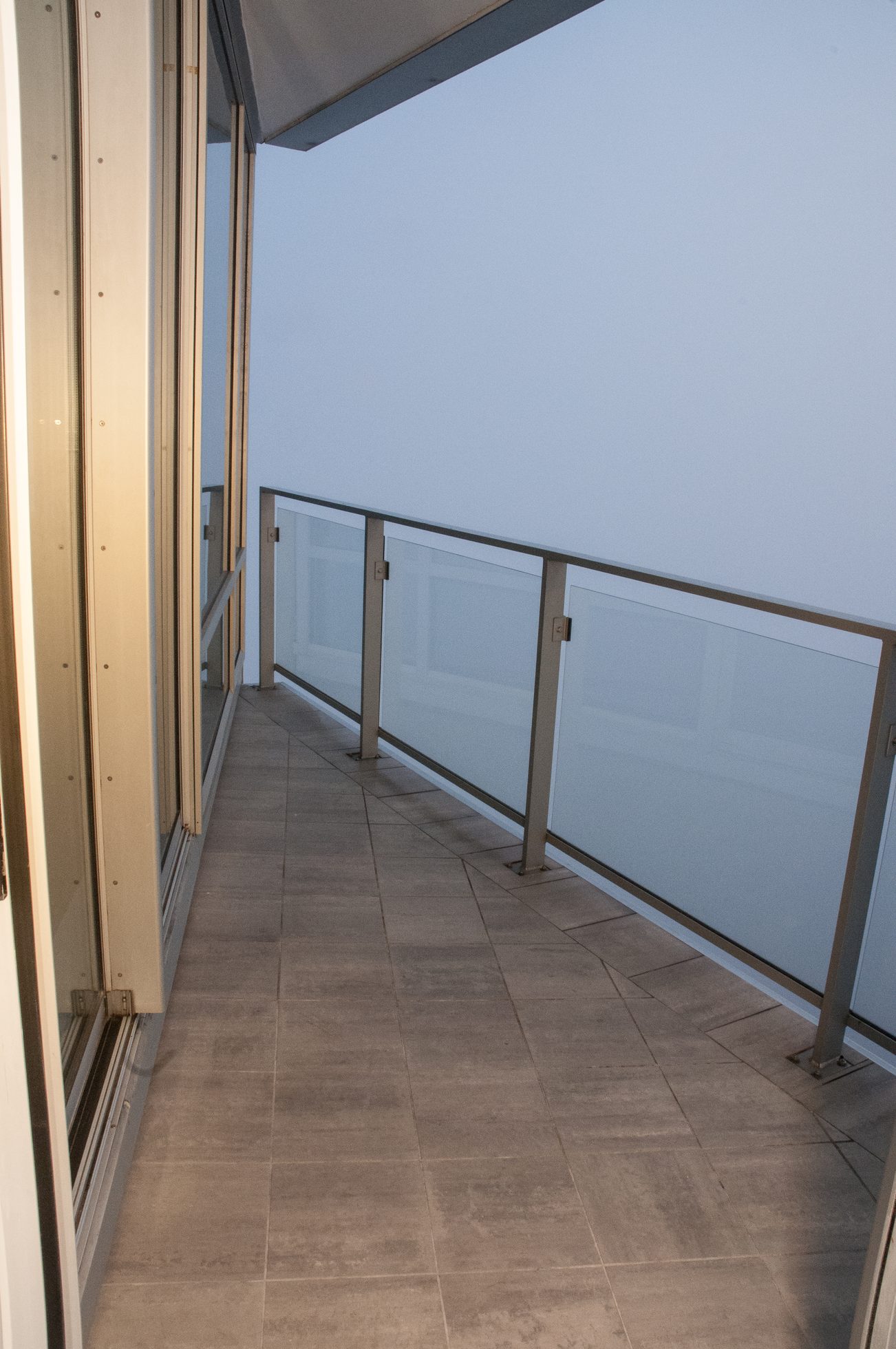 Balcony with glass railing and tiled floor, offering a serene view. - 3201 - 1077 Cordova Street W, Vancouver Downtown