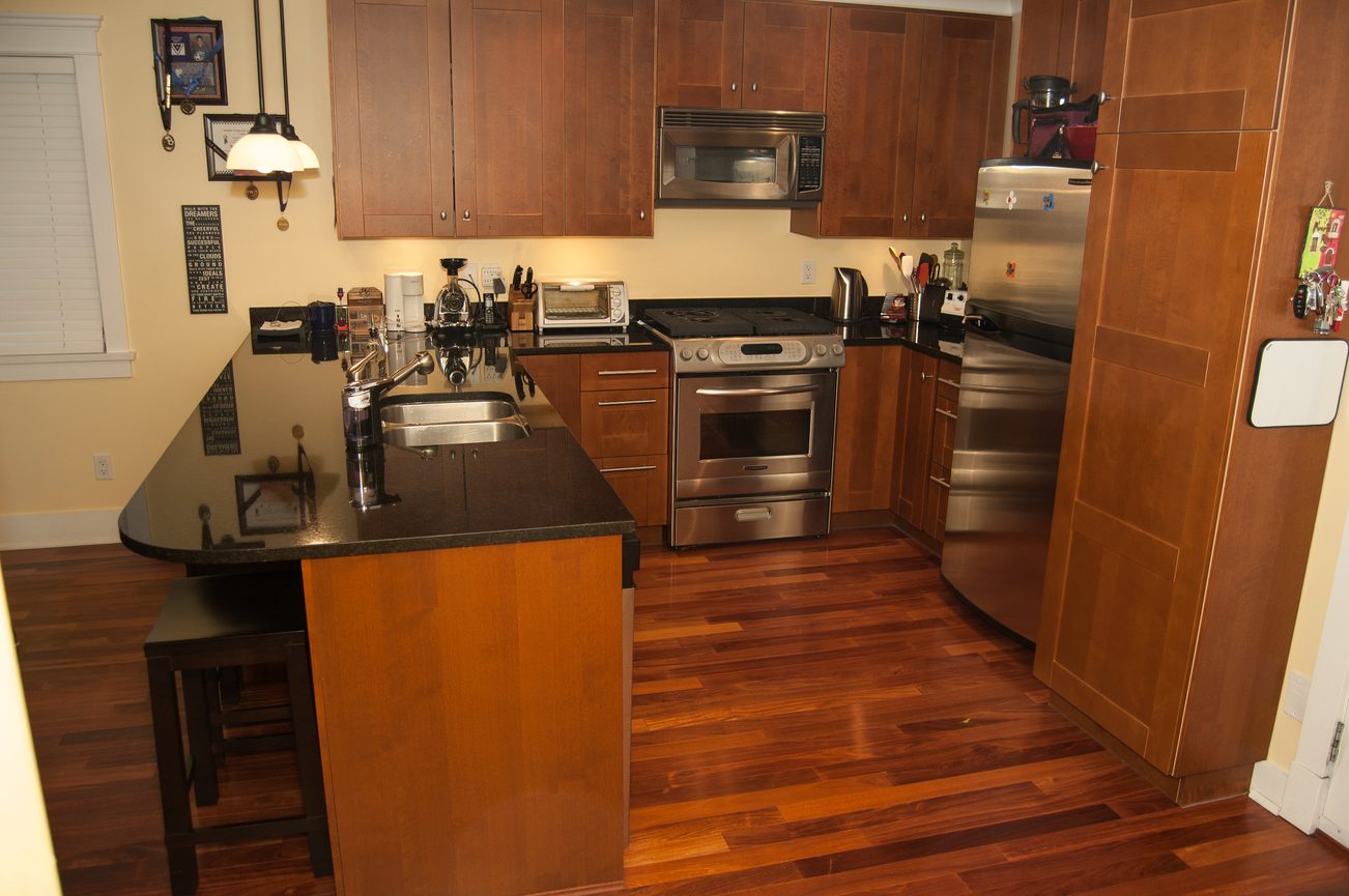 Bright kitchen with dark granite countertops, stainless steel appliances, and hardwood floors. - 221 East 17th Street, North Vancouver