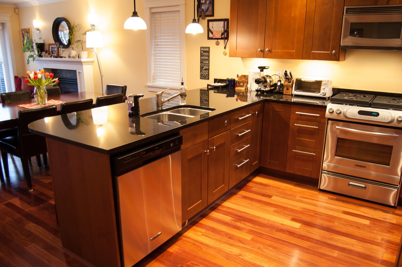 Bright kitchen with dark countertops, stainless steel appliances, and hardwood floors. - 221 East 17th Street, North Vancouver