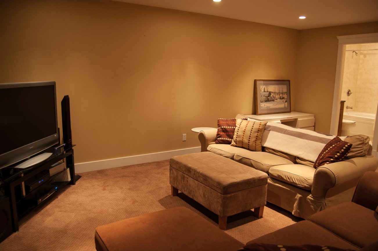 Living room with sectional sofa, ottomans, and a flat-screen TV. - 221 East 17th Street, North Vancouver