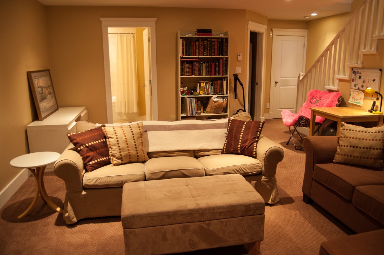 Furnished living room with a sectional sofa, bookshelf, and carpeted floor. - 221 East 17th Street, North Vancouver