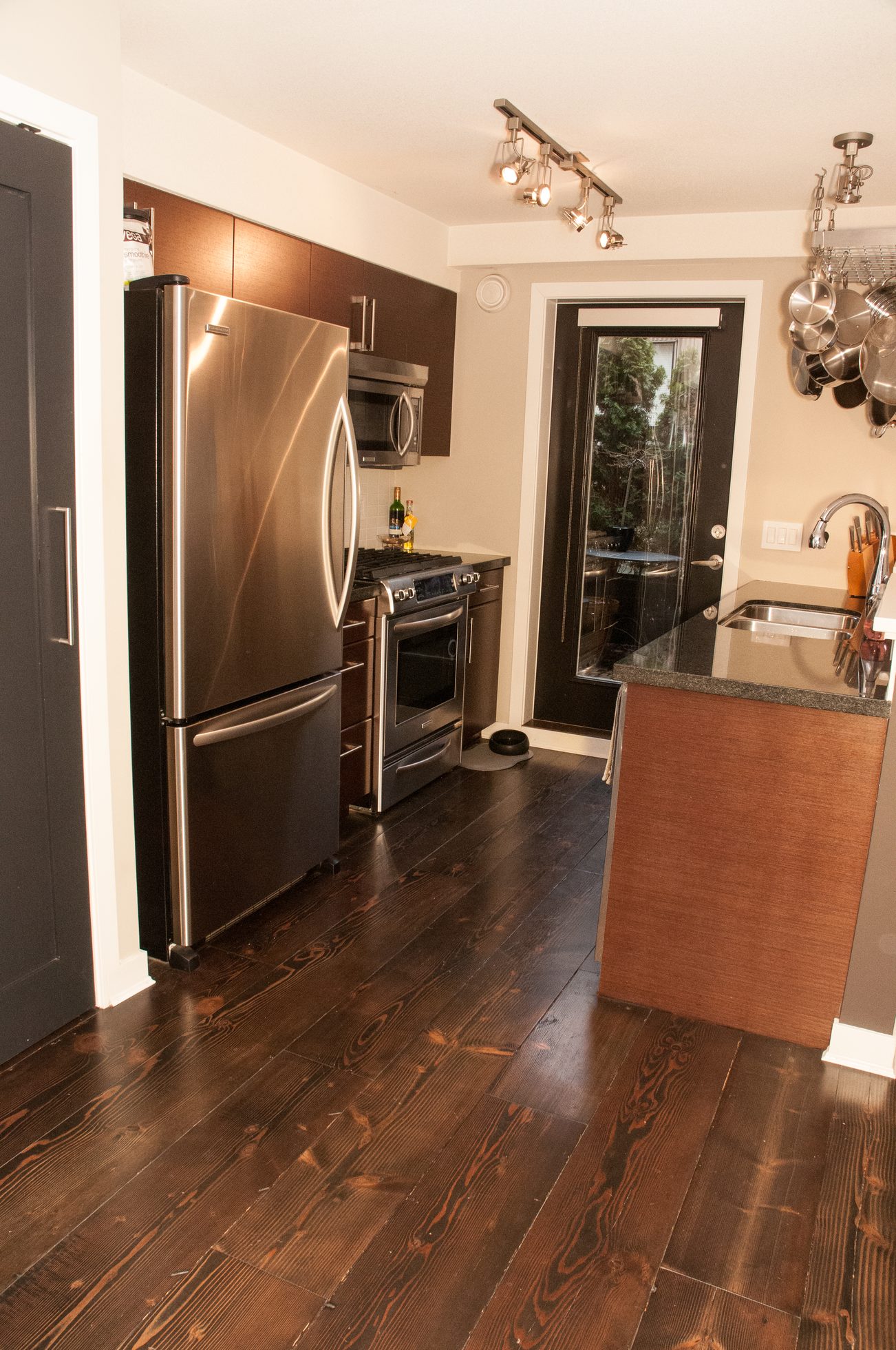 Bright kitchen with dark hardwood floors, stainless steel appliances, and a small island. - 125- 1863 Stainsbury Ave, Vancouver West Side