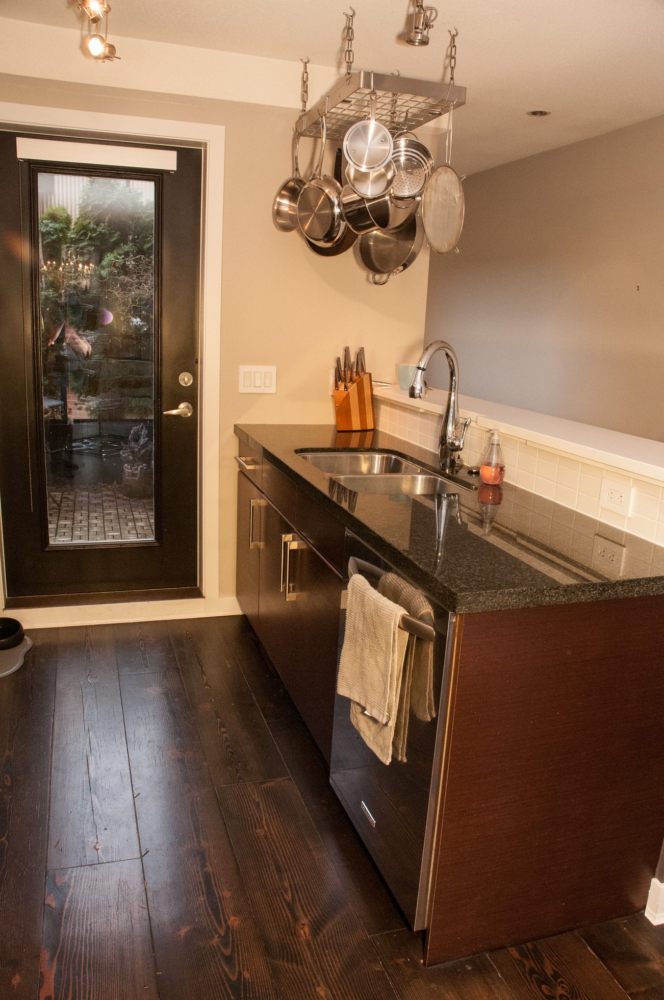 Bright kitchen with dark hardwood floors, granite countertops, and a hanging pot rack. - 125- 1863 Stainsbury Ave, Vancouver West Side