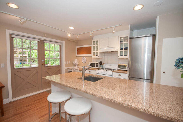 Bright kitchen with granite countertops, white cabinetry, and a stainless steel refrigerator, perfect for a cozy...
