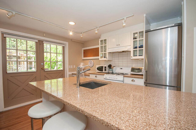 Bright kitchen with granite countertops, white cabinetry, and stainless steel appliances, perfect for a cozy North...