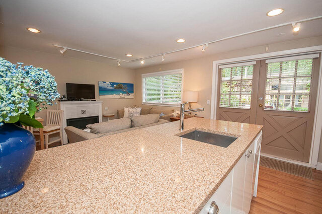 Bright kitchen with granite countertops and hardwood floors, leading to a cozy living area with a fireplace and ocean...