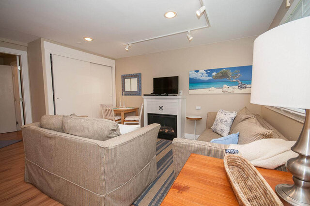 Cozy living room with hardwood floors, a fireplace, and a beach-themed painting. - Address WITHHELD, North Vancouver