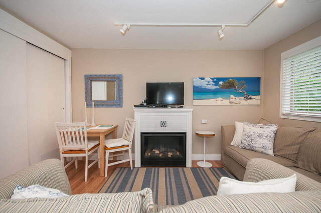 Spacious living room with striped sofas, wooden dining set, and beach-themed artwork. - Address WITHHELD, North Vancouver