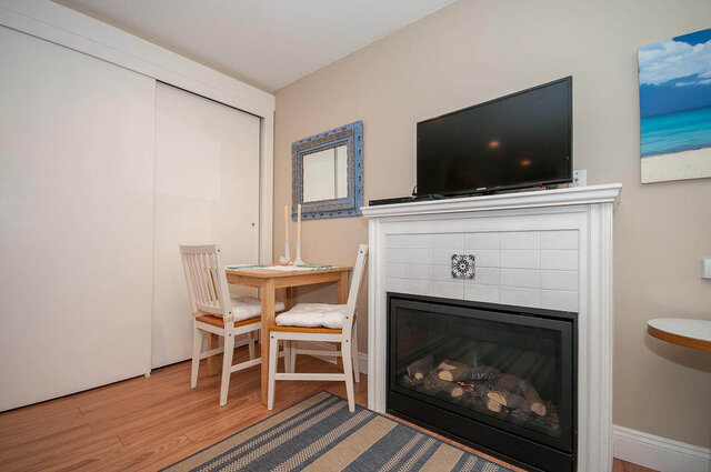 Spacious living room with a cozy fireplace, hardwood floors, and a flat-screen TV above a white mantel. - Address WITHHELD, North Vancouver