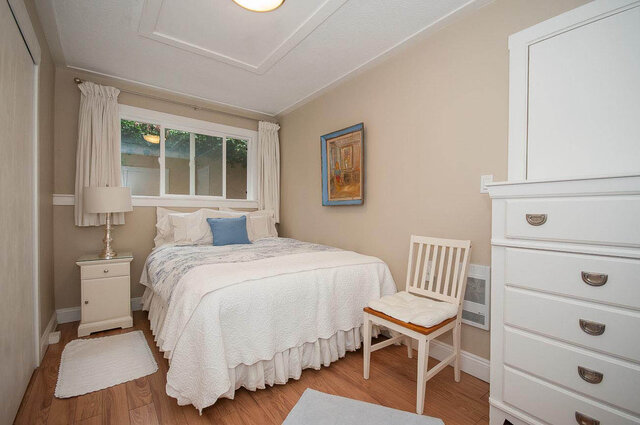 Spacious 1-bedroom bedroom with hardwood floors, white furniture, and a cozy window view. - Address WITHHELD, North Vancouver
