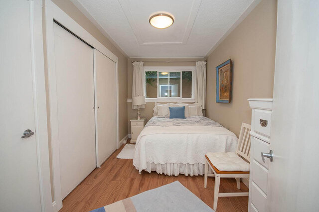Spacious 1-bedroom furnished room with hardwood floors, white walls, and a cozy bed setup. - Address WITHHELD, North Vancouver
