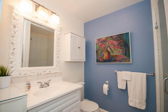 Bright bathroom with white vanity, blue walls, and floral artwork. - Address WITHHELD, North Vancouver