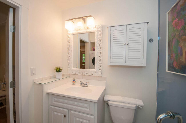 Spacious bathroom with white vanity, decorative mirror, and louvered cabinet. - Address WITHHELD, North Vancouver