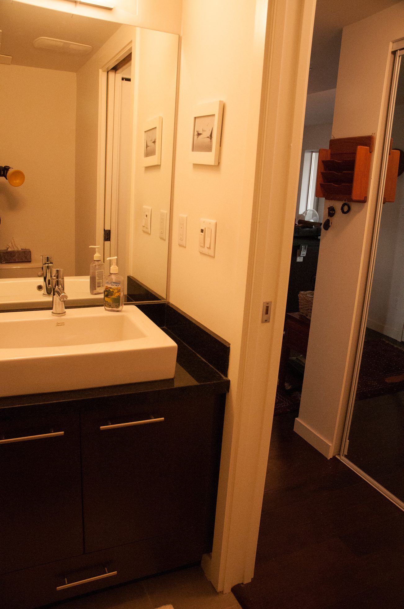 Bright bathroom with black countertops and a white sink, adjacent to a hallway with a wooden shelf. - TH4 - 1288 Chesterfield Ave, North Vancouver