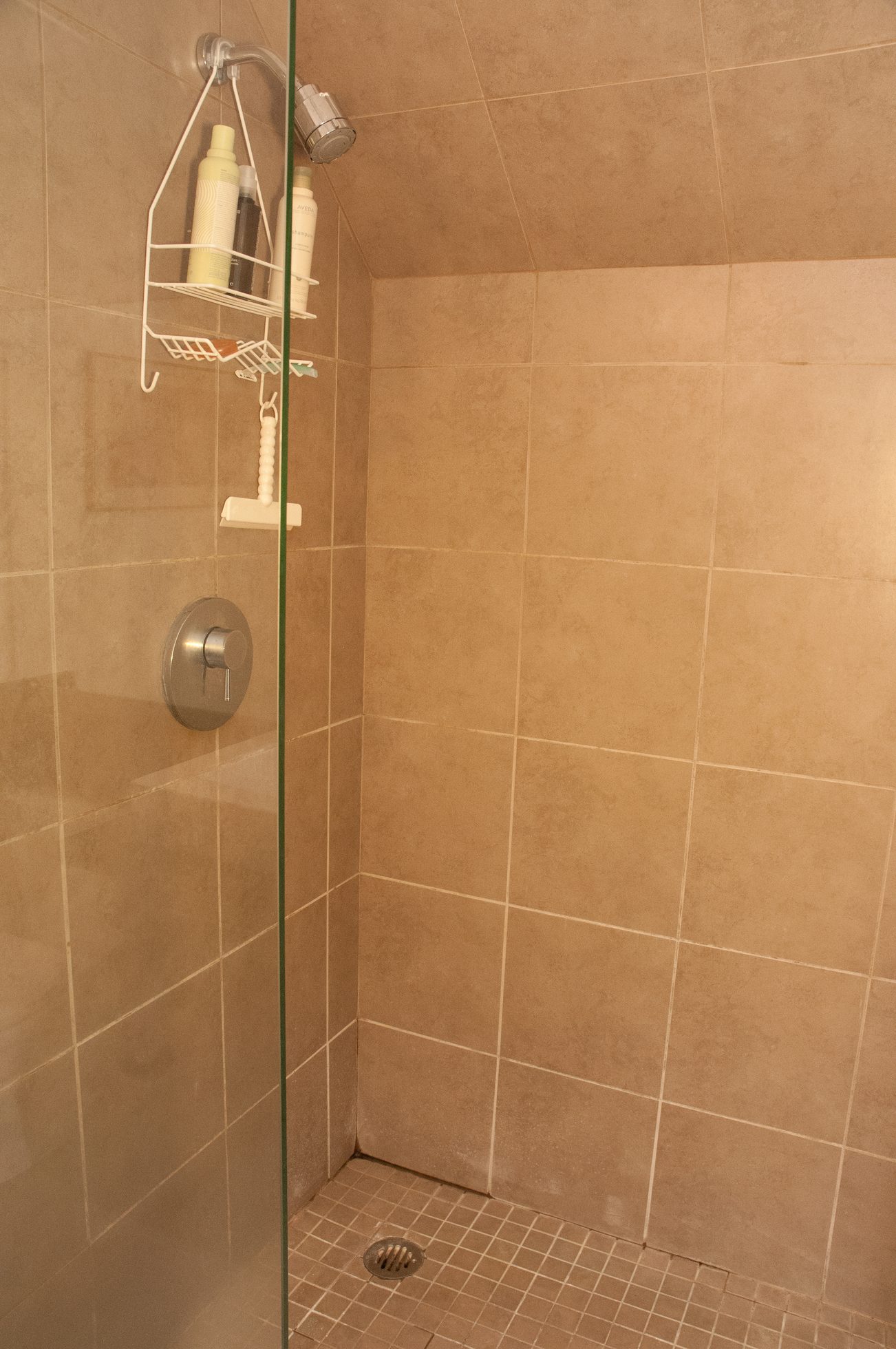 Shower with glass door, beige tiles, and wall-mounted showerhead. - TH4 - 1288 Chesterfield Ave, North Vancouver