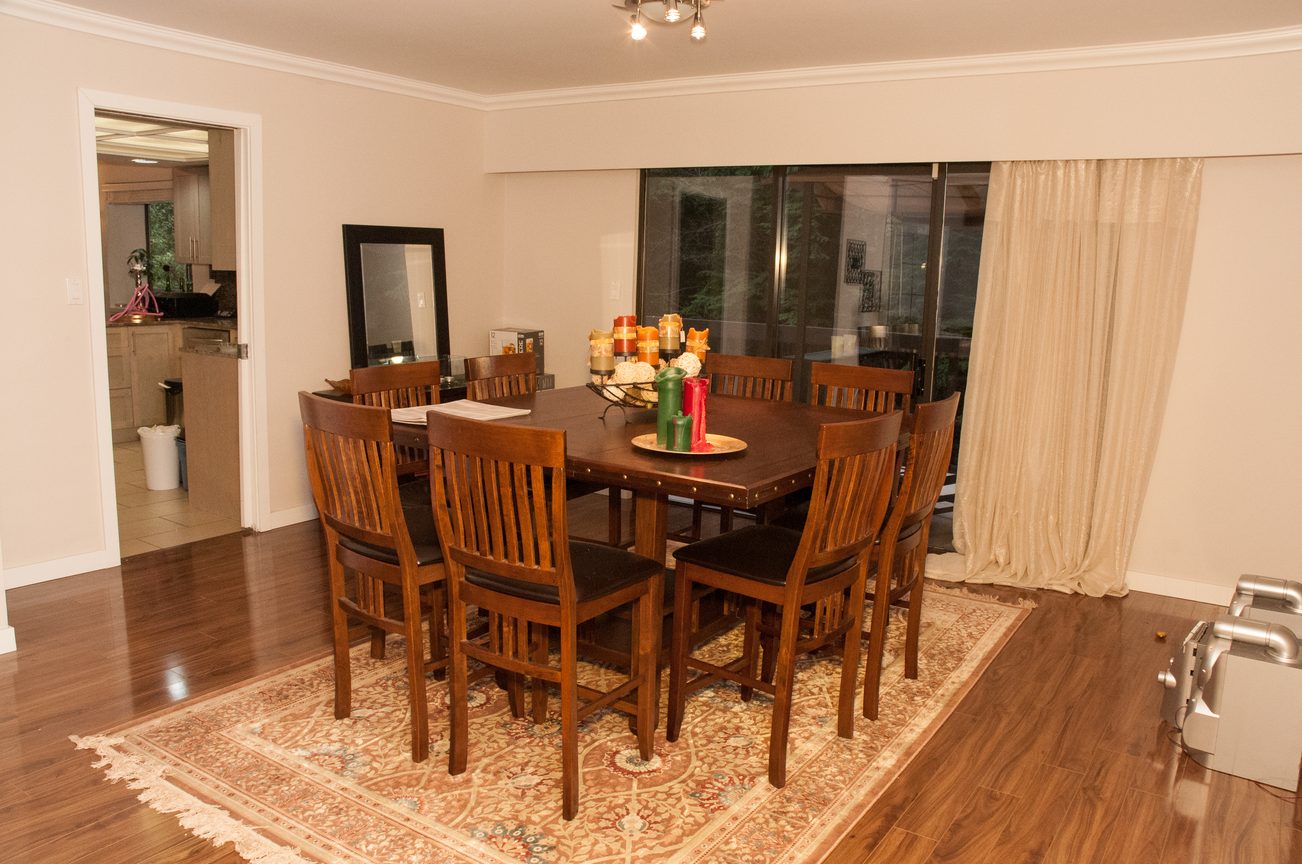 Dining room with wooden table, chairs, and decorative candles, hardwood floors, and sliding glass door. - 5550 Huckleberry Lane, North Vancouver