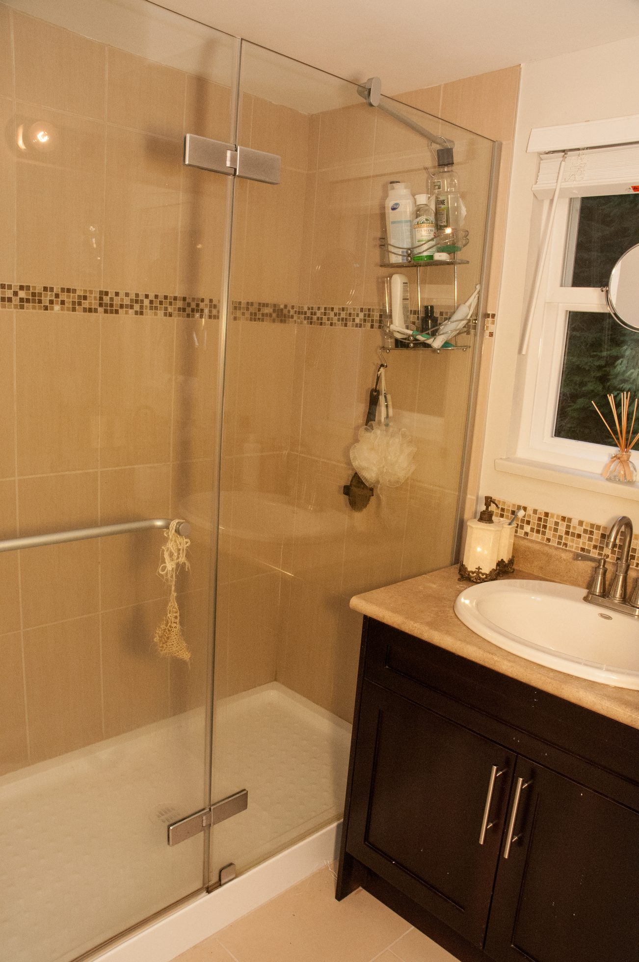 Bathroom with glass shower, beige tile, and dark vanity. - 5550 Huckleberry Lane, North Vancouver