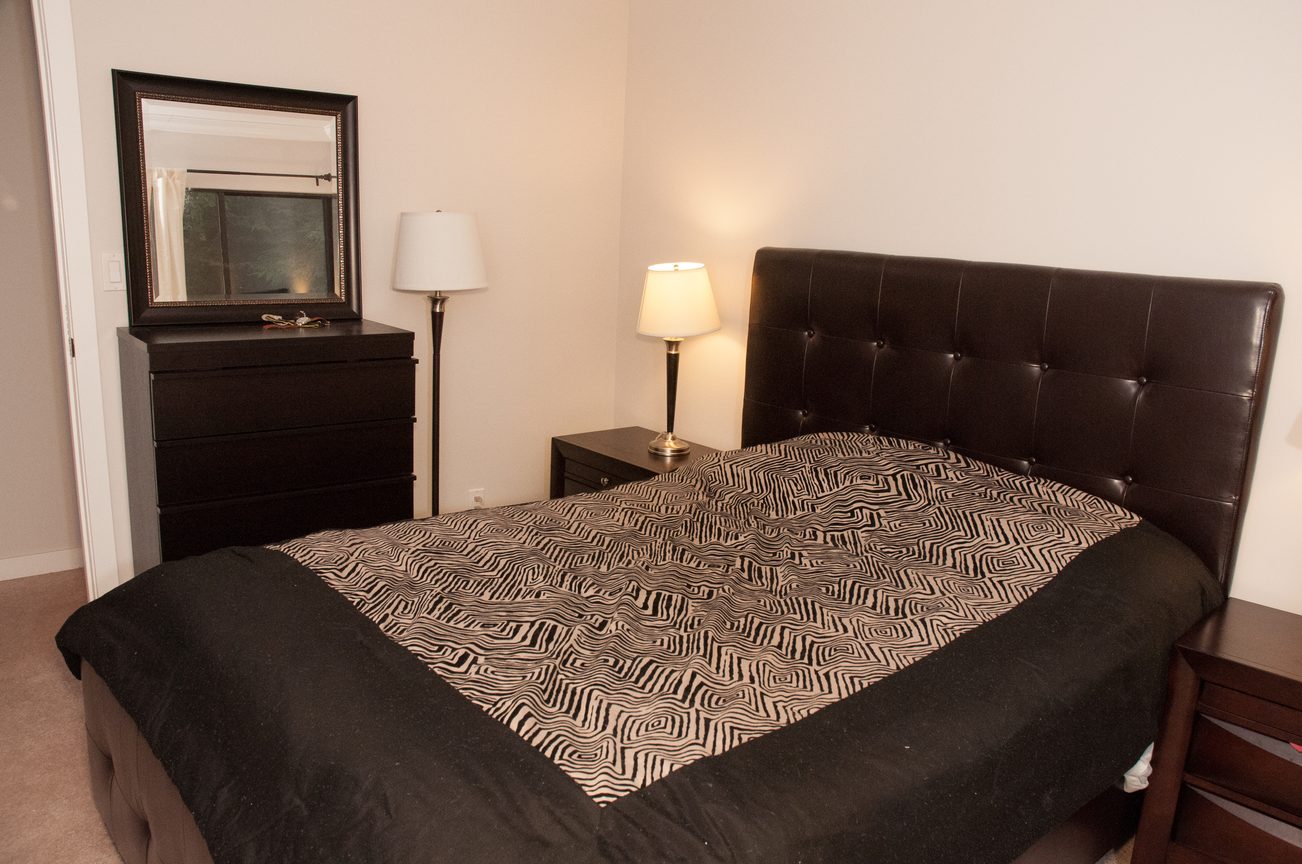 Spacious bedroom with a tufted headboard and patterned bedding. - 5550 Huckleberry Lane, North Vancouver