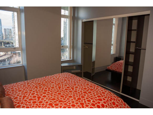 Furnished bedroom with orange patterned bedding and city view. - 1501-1483 Homer Street, Vancouver Downtown