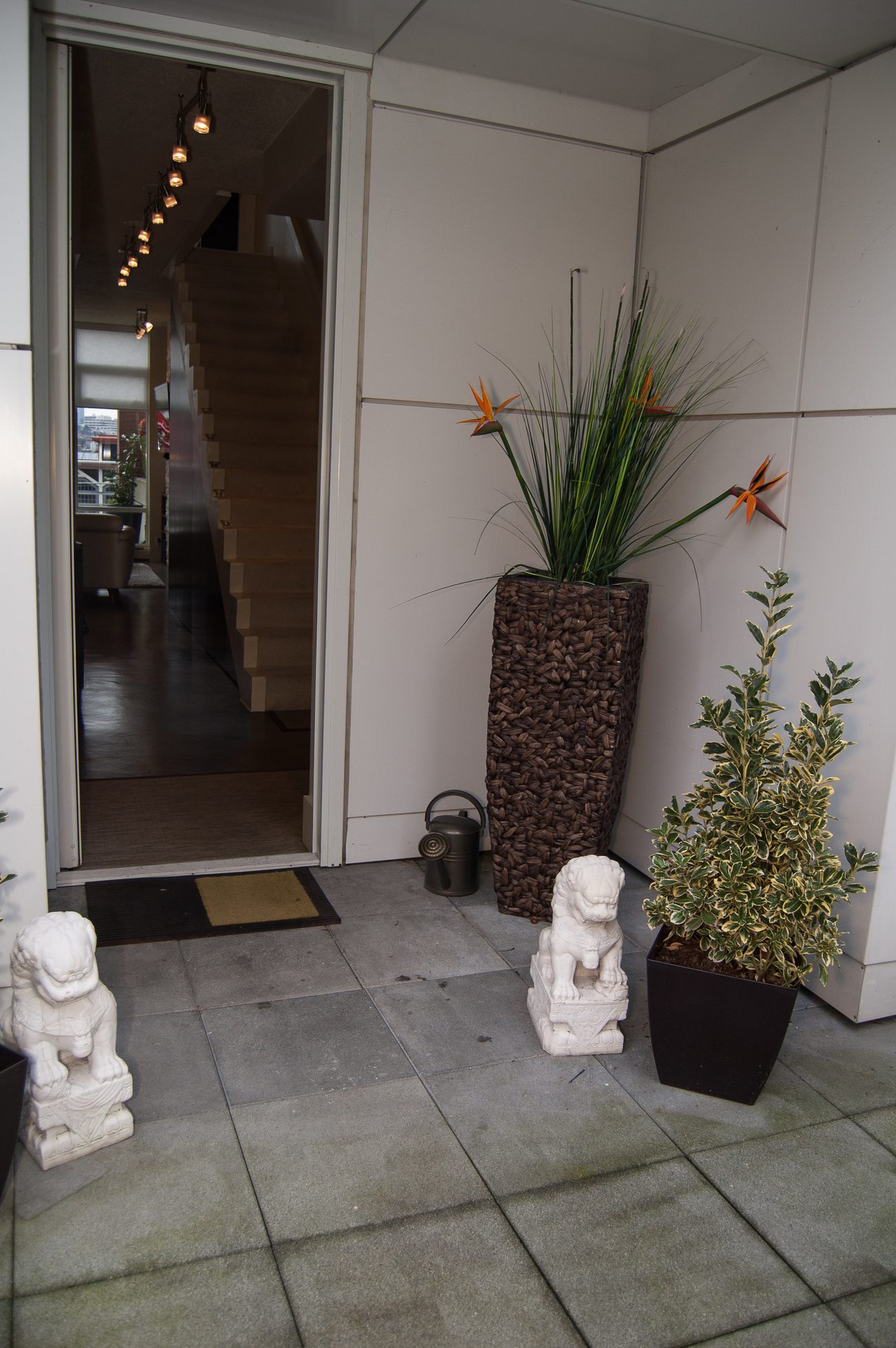 Furnished entryway with stone statues and potted plants, leading to a staircase inside. - TH A- 1199 Marinaside Cres, Vancouver Downtown