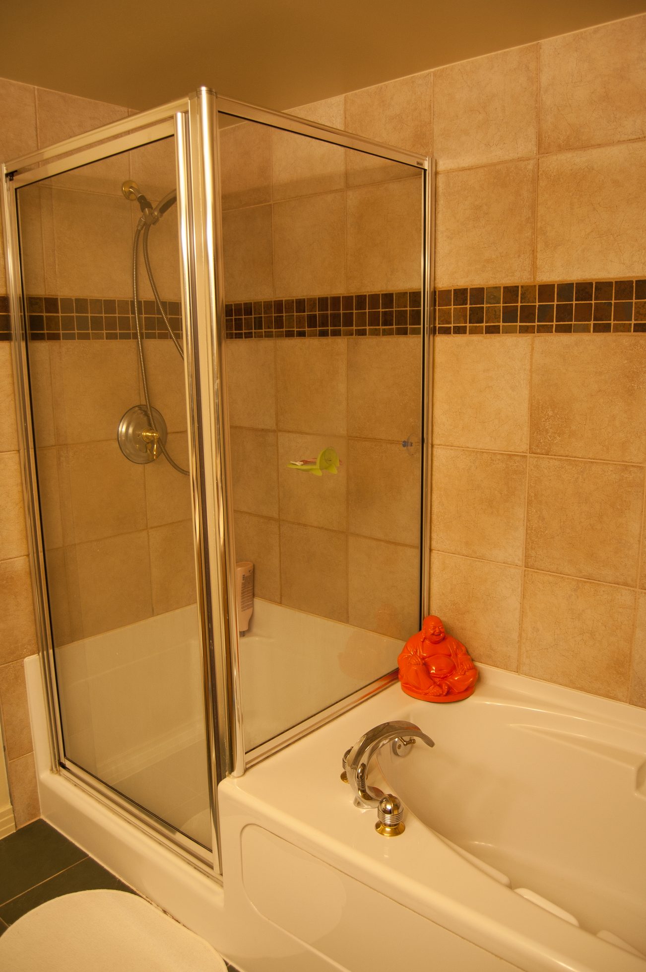 Furnished bathroom with a bathtub, glass shower, and orange Buddha statue. - TH A- 1199 Marinaside Cres, Vancouver Downtown